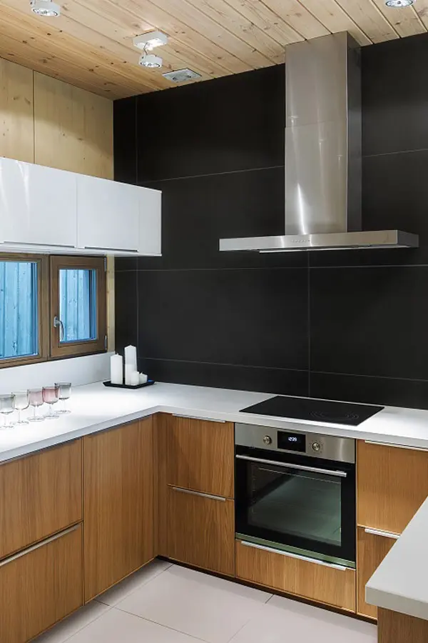 Cocina con contraste de madera y pared negra de azulejos pintados.
