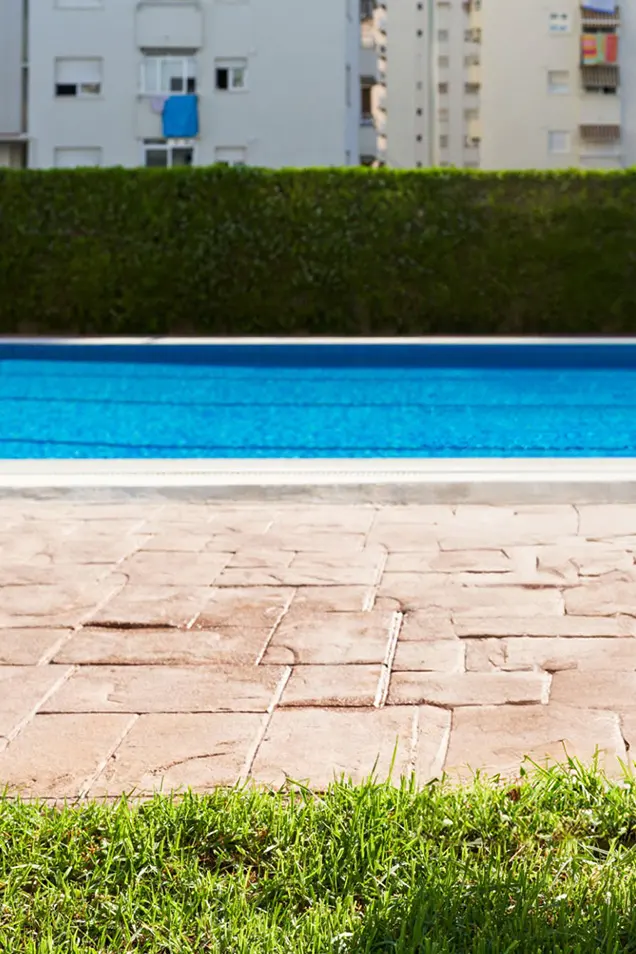 Hormigón impreso en piscina separando el bordillo y el césped